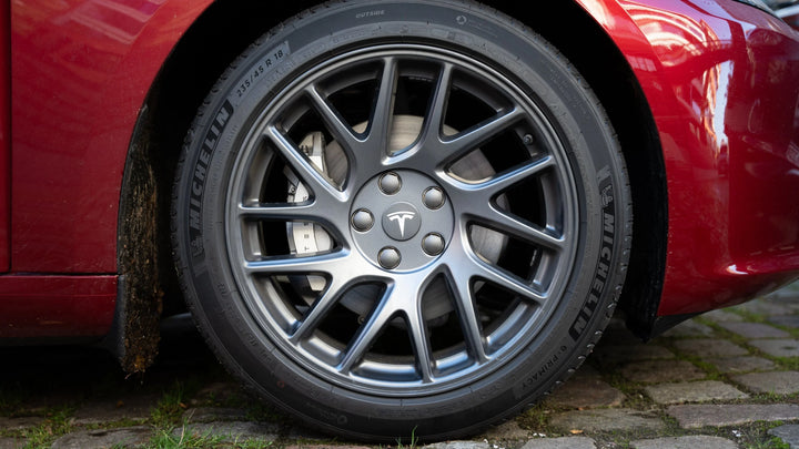 Detailansicht der Tesla Model 3/Y/S Radnabenabdeckungen Logo Felgen, zeigt das präzise silberne Emblem auf schwarzem Hintergrund.